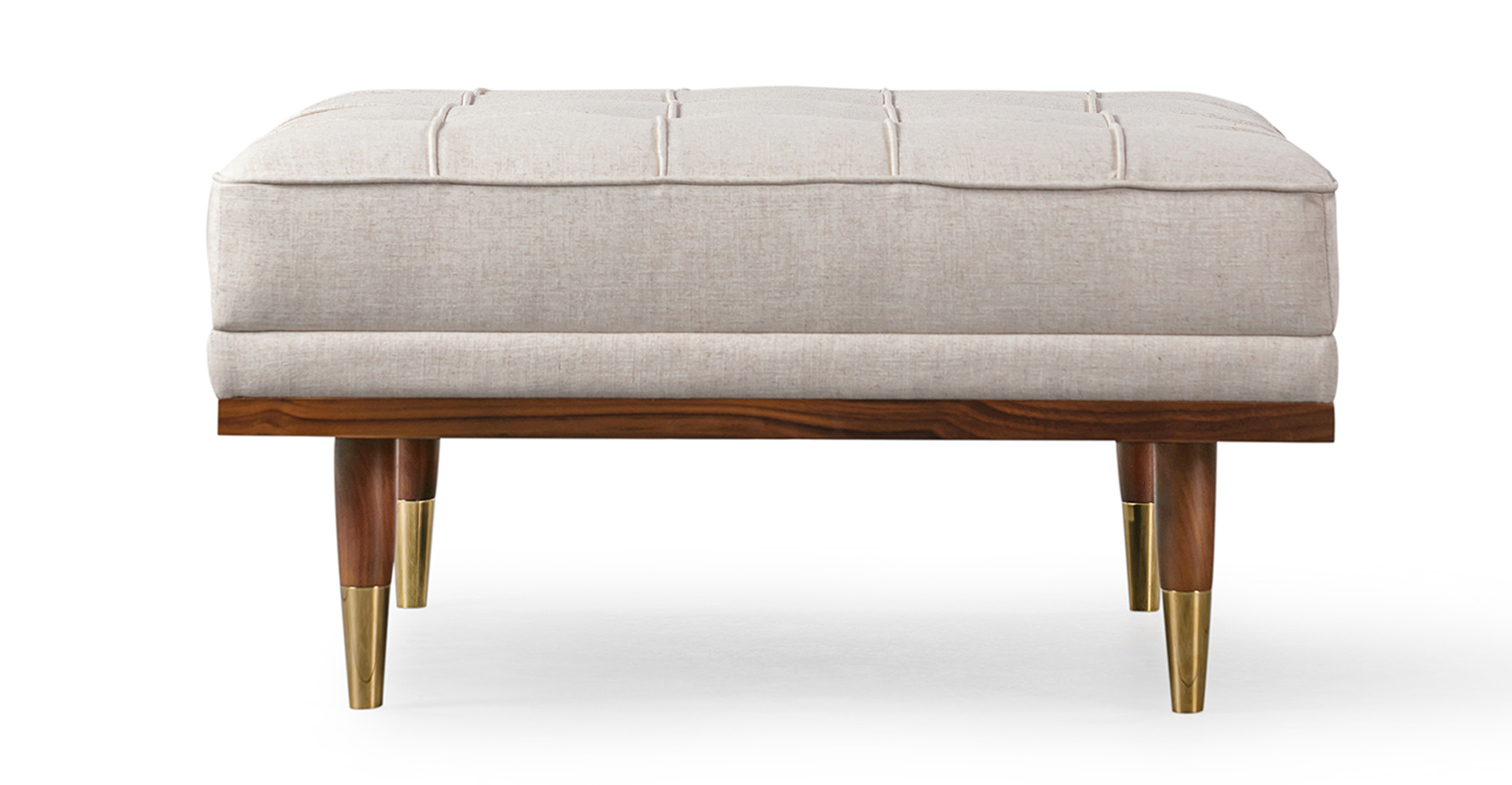 Image shows side picture of Mid-Century Modern Woodrow Box Ottoman in Viscose Woven Oatmeal Fabric. Frame and legs are walnut wood. Legs are brass tipped walnut wood. The cushion is button tufted. 